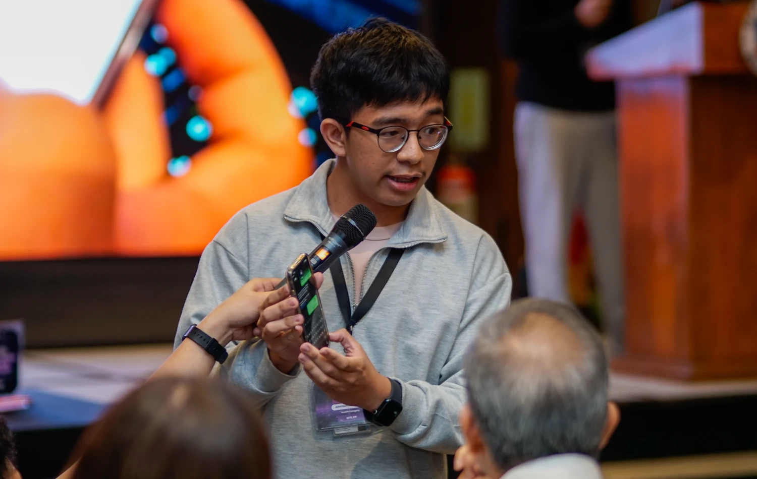 Alexi pitching at the Naga hackathon with a microphone.